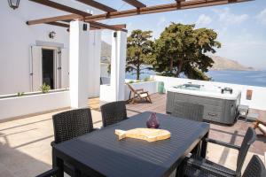 a patio with a table and chairs and a television at Sunny Bay in Agia Marina