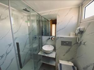 a bathroom with a glass shower and a sink at International Hotel in Rhodes Town