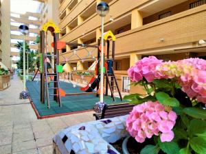 einen Spielplatz in einem Gebäude mit einer Bank und Blumen in der Unterkunft ACV - Costa Caribe II-2ª Linea Planta 4 Sur in Oropesa del Mar