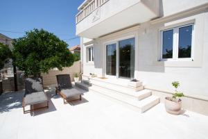 a white house with two chairs and a tree at BUKY HOUSE in Sumartin