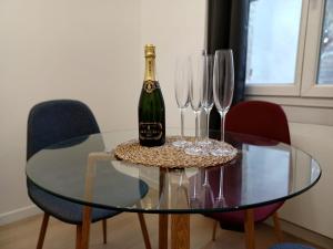 una botella de champán en una mesa de cristal con copas de vino en #SEASONS ֎ Haut Confort Lit King Size ֎ Centre Ville, en Épernay