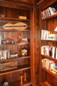 a book shelf with books and a surfboard on it at Altamont Lodge in Newland