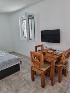 een kamer met een tafel, een televisie en een bed bij NJEGUSI OASIS - a place to charge your batteries! in Njeguši