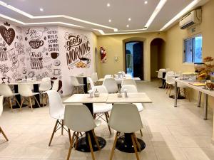 a restaurant with white tables and white chairs at Hotel Mediterraneo in San Miguel de Tucumán