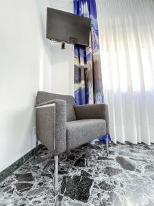 een kamer met een stoel en een tv aan de muur bij B&B Stella in Rovereto