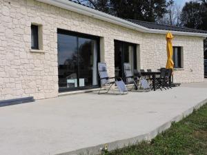 un patio avec des chaises et une table en face d'un bâtiment dans l'établissement Gite du chêne vert - Périgord, à Salignac Eyvigues