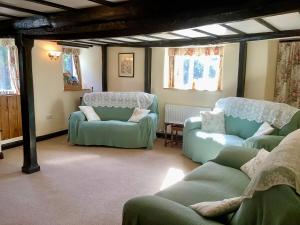 a living room with green chairs and couches at The Barn and Pinn Cottage in Sidmouth