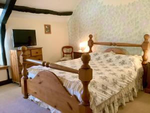 a bedroom with a wooden bed and a tv at The Barn and Pinn Cottage in Sidmouth