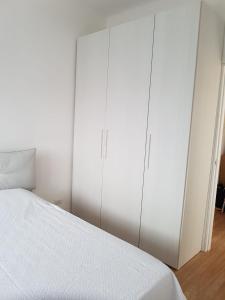 a white bedroom with a bed and two tall cabinets at ETRA Casa Vacanza in Taranto