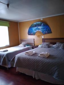 two beds sitting next to each other in a bedroom at hostal geminis ,phillipi 653 centro in Puerto Natales