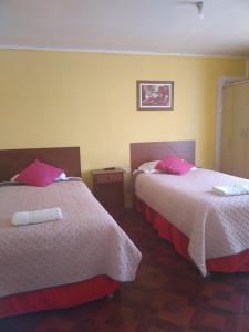2 camas en una habitación de hotel con almohadas rosas en hostal geminis ,phillipi 653 centro en Puerto Natales