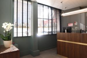 ein Büro mit Fenstern und einem Schreibtisch mit einer Vase aus Blumen in der Unterkunft Timhotel Paris Gare Montparnasse in Paris