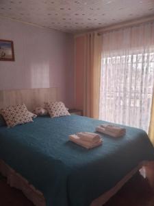 1 dormitorio con 1 cama azul grande y 2 toallas en hostal geminis ,phillipi 653 centro en Puerto Natales