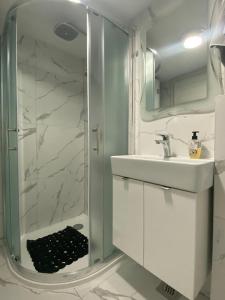 Mate Apartments في قشتيلا: حمام أبيض مع دش ومغسلة