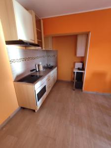 a kitchen with orange walls and white cabinets at Apartman Tramonto in Motovun