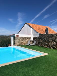 a house with a swimming pool next to a stone wall at CASA DAS 4 MARIAS in Pinheiro de Ázere