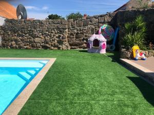 a artificial grass yard with a play house and a swimming pool at CASA DAS 4 MARIAS in Pinheiro de Ázere