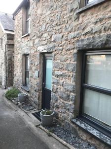 a brick building with a black door and two plants at Aelfor Cozy Cottage in Barmouth