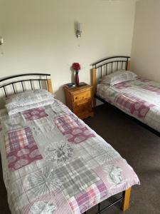 a room with two beds and a table with a night stand at The Red Lion Great Offley in Offley