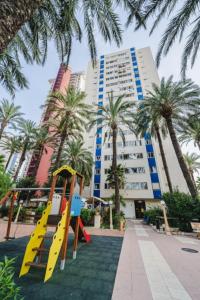 a playground in front of a building with palm trees at El Rincón Playero de María II TOTALMENTE REFORMADO ABRIL 2022 in Benidorm