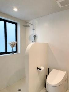 a white bathroom with a toilet and a window at Atelier Lumi at Lumicollection in Miami