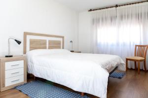 ein Schlafzimmer mit einem großen weißen Bett und einem Stuhl in der Unterkunft Ático Mirador Santa Tecla A Guarda in A Guarda