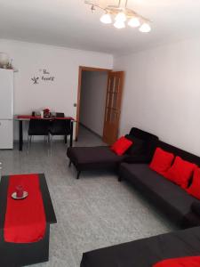 uma sala de estar com um sofá preto e almofadas vermelhas em habitación pequeña en piso compartido con 2 adultos y 1 perrito em Valência