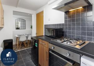 a kitchen with a stove and a counter top at FLATZY - Modern Apartment Close to Football Stadiums in Liverpool