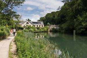 two people walking down a path next to a river at contemporary quiet countryside retreat in Horsley