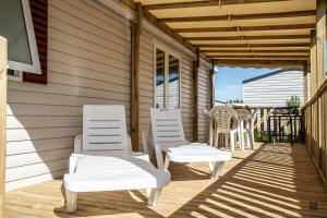 twee witte stoelen en een tafel op een veranda bij amorosa mobil home in Canet-en-Roussillon