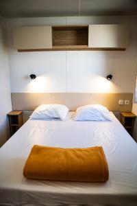 a large white bed with an orange towel on it at amorosa mobil home in Canet-en-Roussillon