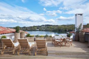 une terrasse avec des chaises et une table et une vue sur le lac dans l'établissement Brindos, Lac & Château - Relais & Châteaux - Anglet Biarritz, à Anglet