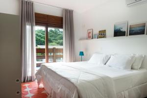 ein weißes Bett in einem Schlafzimmer mit einem Fenster in der Unterkunft Haute Haus - Guest House in Florianópolis