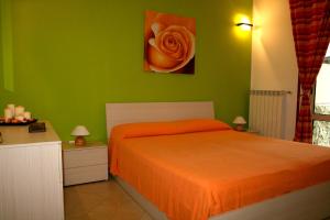1 dormitorio con cama de color naranja y pared verde en Appartamento Giove, en Otranto