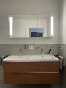 y baño con lavabo blanco y espejo. en Traumapartment Murmeltier Tirol, en Grins