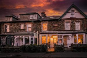 a large brick house with a sunset in the background at Glen Wynne - FREE off-site Health Club access with Pool, Sauna, Steam Room & Gym in Windermere