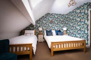 2 camas en una habitación con papel pintado floral en Glen Wynne - FREE off-site Health Club access with Pool, Sauna, Steam Room & Gym, en Windermere