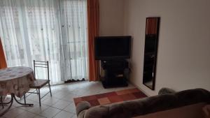 a living room with a couch and a television at Abigel Thermal Apartman in Bük