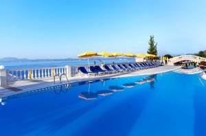 a large swimming pool with blue chairs and umbrellas at Sunshine Corfu Hotel And Spa in Nisaki