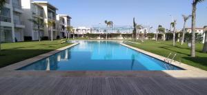 una piscina en un parque con palmeras y edificios en Casabay Appart Vue Sur Piscine en Sidi Rahal