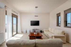a living room with a couch and a tv at Diamond Hill Villa in Koskinou