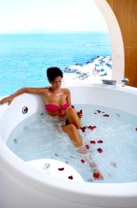 a woman sitting in a bath tub in the ocean at Sunshine Corfu Hotel And Spa in Nisaki