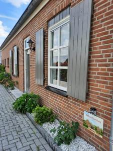 a brick building with a window and some plants at B&B De Raamberg in Zundert
