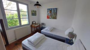 ein Zimmer mit zwei Betten und einem Fenster in der Unterkunft Maison ossature bois in Lège