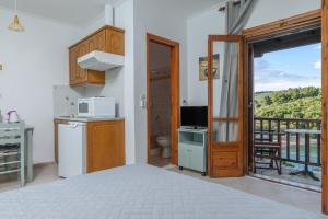 a room with a bed and a kitchen with a balcony at Studios Avra in Agios Georgios