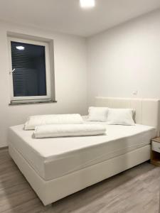 ein großes weißes Bett in einem Zimmer mit Fenster in der Unterkunft Perfect Place apartment in Kranj