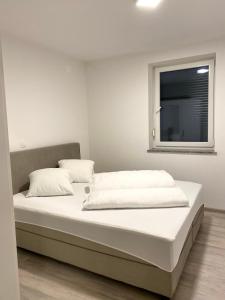 ein Bett mit weißer Bettwäsche und ein Fenster in einem Zimmer in der Unterkunft Perfect Place apartment in Kranj