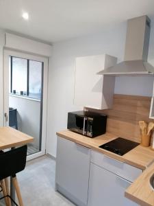 a kitchen with white cabinets and a black microwave at Chambre de Brunemont in Diéval