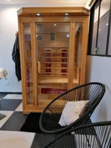 uma cadeira com uma almofada em frente a uma caixa de vidro em Chambre de Brunemont em Diéval