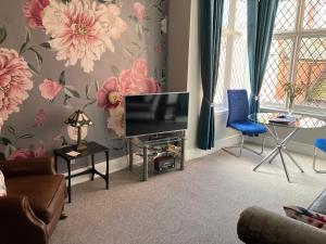 sala de estar con TV y silla azul en Rooftops - bijou sister apartment to Assembly View en Ludlow